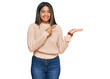 © Krakenimages.com - Young latin girl wearing wool winter sweater amazed and smiling to the camera while presenting with hand and pointing with finger.