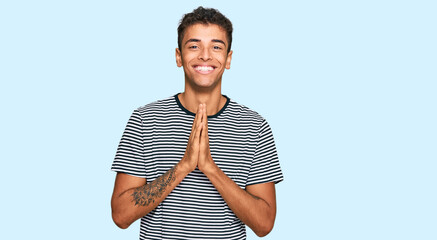 Young handsome african american man wearing casual clothes praying with hands together asking for forgiveness smiling confident.