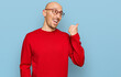 © Krakenimages.com - Bald man with beard wearing casual clothes and glasses smiling with happy face looking and pointing to the side with thumb up.