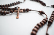 Wooden rosary with metal crucifix on a white surface  