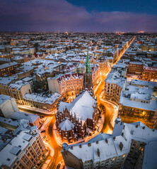 Riga city panorama in winter time. Street lights glowing in blue hour. Snowy rooftops. Iconic buildings and architecture. Drone footage. 