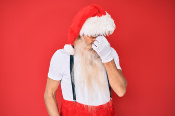 Wall Mural - Old senior man with grey hair and long beard wearing white t-shirt and santa claus costume tired rubbing nose and eyes feeling fatigue and headache. stress and frustration concept.