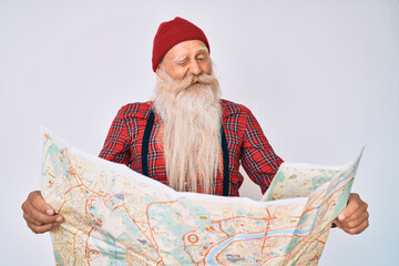 Wall Mural - Old senior man with grey hair and long beard holding city map winking looking at the camera with sexy expression, cheerful and happy face.