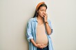 © Krakenimages.com - Beautiful hispanic woman expecting a baby, touching pregnant belly looking stressed and nervous with hands on mouth biting nails. anxiety problem.