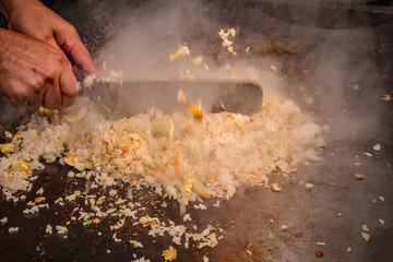 Chef cooking fried rice on grill.