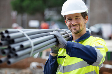 happy construction worker on site holding pipe