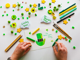 drawing a green hat of st. patrick. greenish background. saint patrick's day concept.