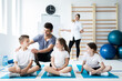 © Photographee.eu - Kids sitting on blue yoga mats with their professional physician