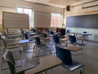 © Jon - A Shadowy, Empty Classroom in a School with Chairs Facing a Chalkboard on a Sunny Day