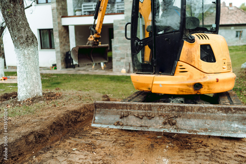 Obraz Dibond Landscaping works at home construction site using excavator and mini bulldozer