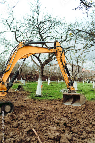 Obraz Dibond Landscaping works at home construction site using excavator and mini bulldozer
