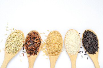 Five dry organic rice seed collection in light brown wooden spoon on white background