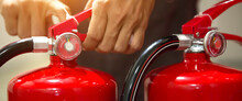Firefighter Pulling The Safety Pin At The Handle Of The Red Fire Extinguishers Tank In The Building Concepts Of Prevent Case For Emergency Rescue And Fire Training.