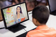© vectorfusionart - Mixed race schoolboy using computer on video call with female teacher
