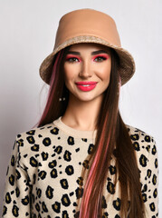 Wall Mural - Portrait of smiling woman with colored hair in leopard pattern print pullover sweater and hat looking at camera over grey background. Blowing kiss on white background