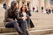 © Cavan Images - Cheerful friends talking while sitting on steps