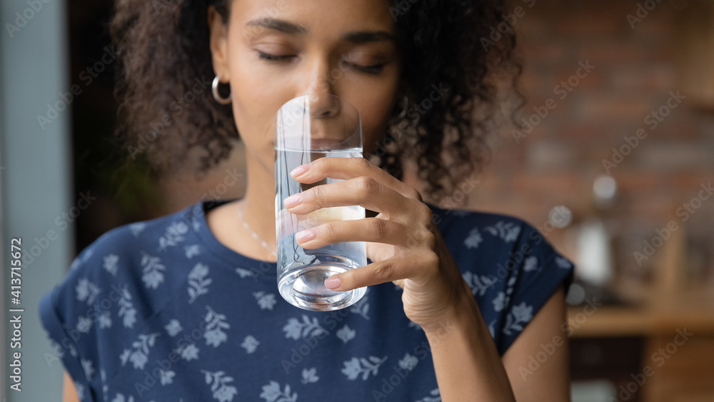 Close up satisfied African American young woman enjoying, drinking pure fresh mineral water with closed eyes, holding glass, healthy lifestyle and good daily habit concept, body and skin care - obrazy, fototapety, plakaty 