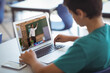 © vectorfusionart - Male caucasian student having a video call with male teacher on laptop at school