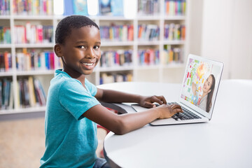 Poster - Portrait of male african american student having a video call with female teacher on laptop at libra