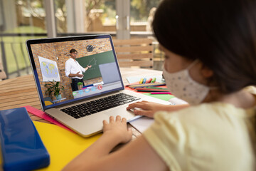 Poster - Female student wearing face mask having a video call with male teacher on laptop at school