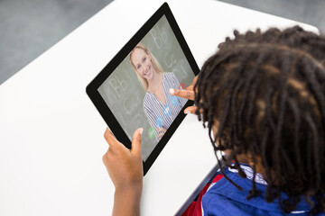 Wall Mural - Male student having a video call with female teacher on digital tablet at school