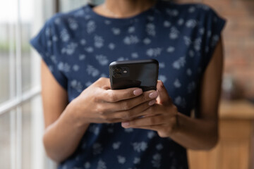 Close up African American young woman holding smartphone in hands, browsing apps, typing on screen, using phone, writing message in social network, chatting or shopping online, surfing internet