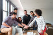 © Cavan Images - Happy business people doing hands stack at desk in office
