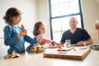 © Cavan Images - Girl picking pizza slice while sitting with family at dining table in home