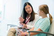© Cavan Images - Pediatrician talking with girl while sitting on chair in hospital waiting room