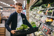 © Jacob Lund - Shop assistant restocking the produce section shelves