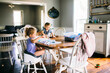 © Cavan Images - Sister painting while brother sitting on dining table at home