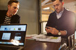 © Cavan Images - Businessman using mobile phone while sitting with male colleague in office