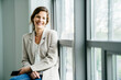 © Cavan Images - Portrait of smiling businesswoman sitting by window in office