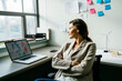 © Cavan Images - Businesswoman with arms crossed sitting on chair at desk in office