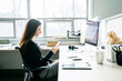 © Cavan Images - Businesswoman using smart phone while sitting on chair at desk in office