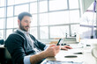 © Cavan Images - Businessman using smart phone while sitting at desk in office