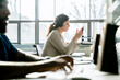 © Cavan Images - Businesswoman using smart phone while sitting by colleague in office