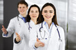 © rogerphoto - Doctors are standing as a team while offering their helping hands for shaking hand or saving people's life. Physicians are ready to help their patients. Medical help, insurance in health care, best