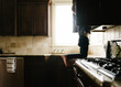 © Cavan Images - Boy searching something in cabinet while kneeling on kitchen counter at home