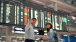 © Pixza - Couple traveler checking flight schedule board in airport terminal
