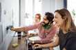 © Cavan Images - Happy businessman marking on paper while sitting with colleagues in office
