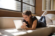 © Cavan Images - Smiling woman using digital tablet while lying on sofa at home