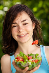 Wall Mural - Girl eating fresh vegetable salad
