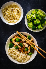 Chicken nuggets with noodles and oyster mushrooms on black table
