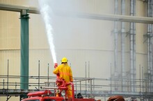 Fireman Use Fire Hose Water Spray From Fire Truck To The Large Chemical Tank In Part Of Fire Drill Or Emergency Drill Training In Tank Farm At Onshore, Oil And Gas Or Chemical Factory.