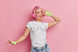 © wayhome.studio  - Positive upbeat Asian teenage girl feels carefree moves with rhythm of music wears stereo headphones on ears dressed in casual clothing isolated on pink bacjground has rosy hair listens favorite song