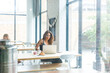 © Cavan Images - Woman using laptop computer while sitting in cafe with friend in background seen through window