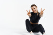 © Liubov Levytska - Sport and women. Healthy and active fitness woman sitting on floor, resting after workout training, showing v-signs and smiling at camera. Sportswoman achieve goal in gym, white background