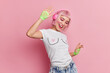 © wayhome.studio  - Positive millennial girl with pink hair enjoys listening music via headphones dances with rhythm of music has professional makeup dressed casually isolated over rosy background. People entertainment