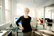 © Cavan Images - Portrait of smiling businesswoman standing by table in office